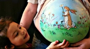 Художничка рисува върху коремите на бременни