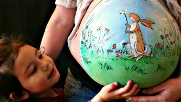 Художничка рисува върху коремите на бременни